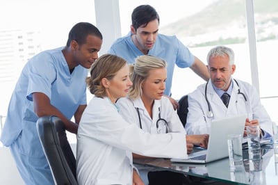 Serious medical team using a laptop in a bright office